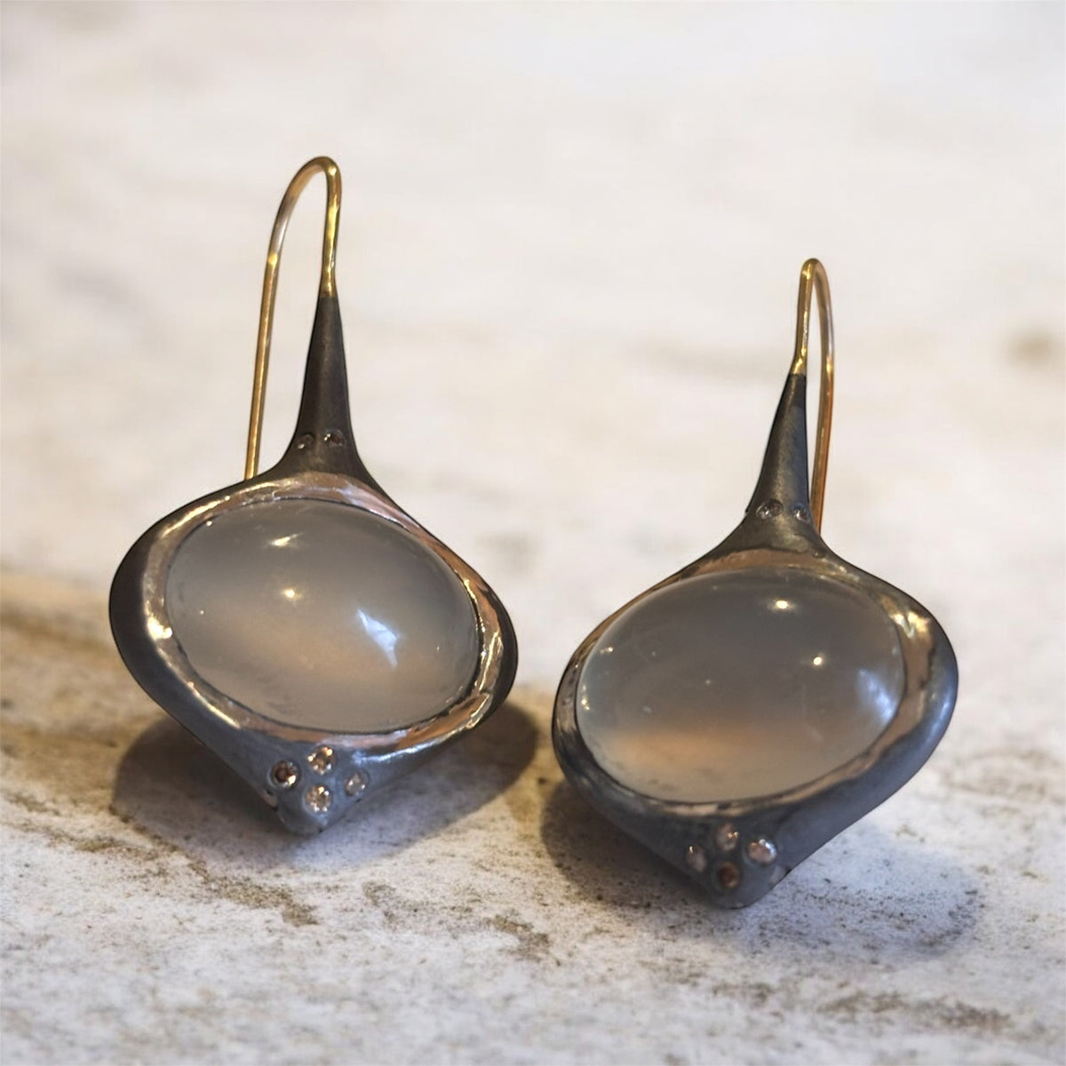 Additional view of Grey Oval Moonstone Earrings with Brown Diamond Accents — Oval grey Moonstone cabochons are set in silver, featuring 14k gold affixed earwire, brown diamond accents on top and bottom